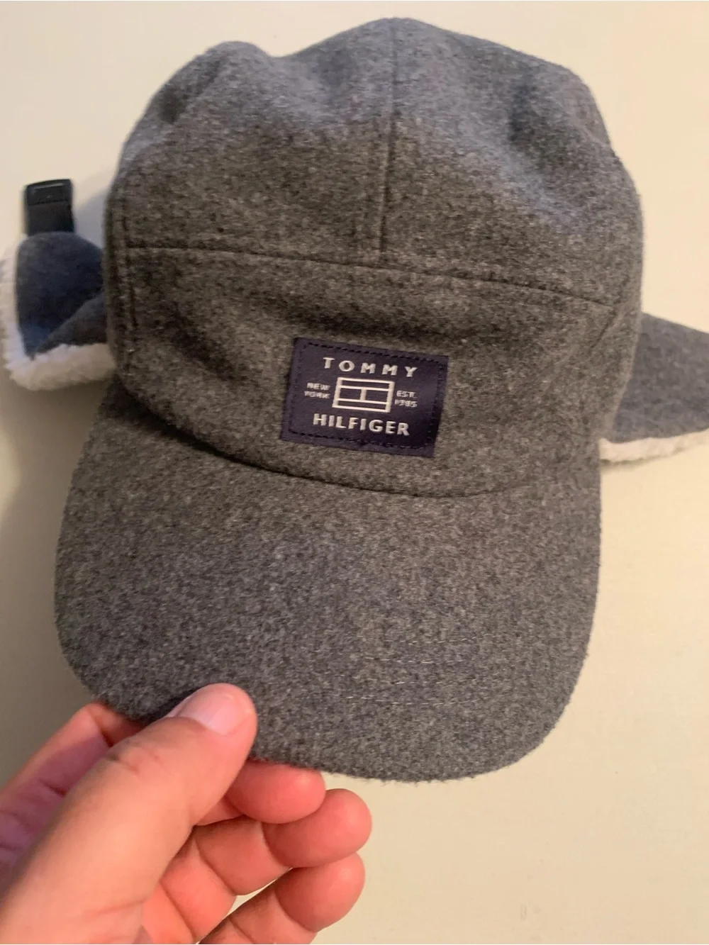 Tommy Hilfiger fleece winter cap featuring fold-down ear flaps with white sherpa